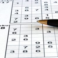 数读网内容主笔在书桌前整理在线数独题目难度标注笔记，桌上摊开方格纸与铅笔，光线自然