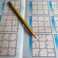 题库校验人员在双屏电脑前比对在线数独题目候选数结构，屏幕上是密集的九宫格数据